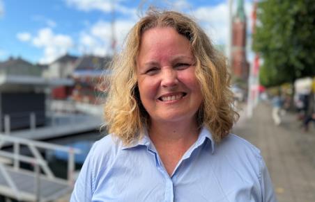 Portrettbilde av en kvinne som smiler med blå bluse.