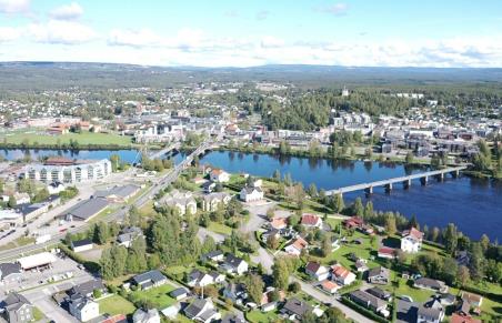 Et dronebilde av en by med en elv som renner gjennom byen og tre bruer som krysser elva. Elverum sentrum med Glomma og bruene.