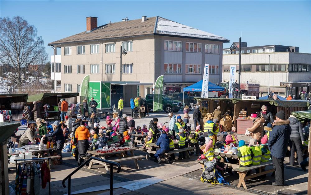 En åpen plass ute med mange folk og boder. - Klikk for stort bilde