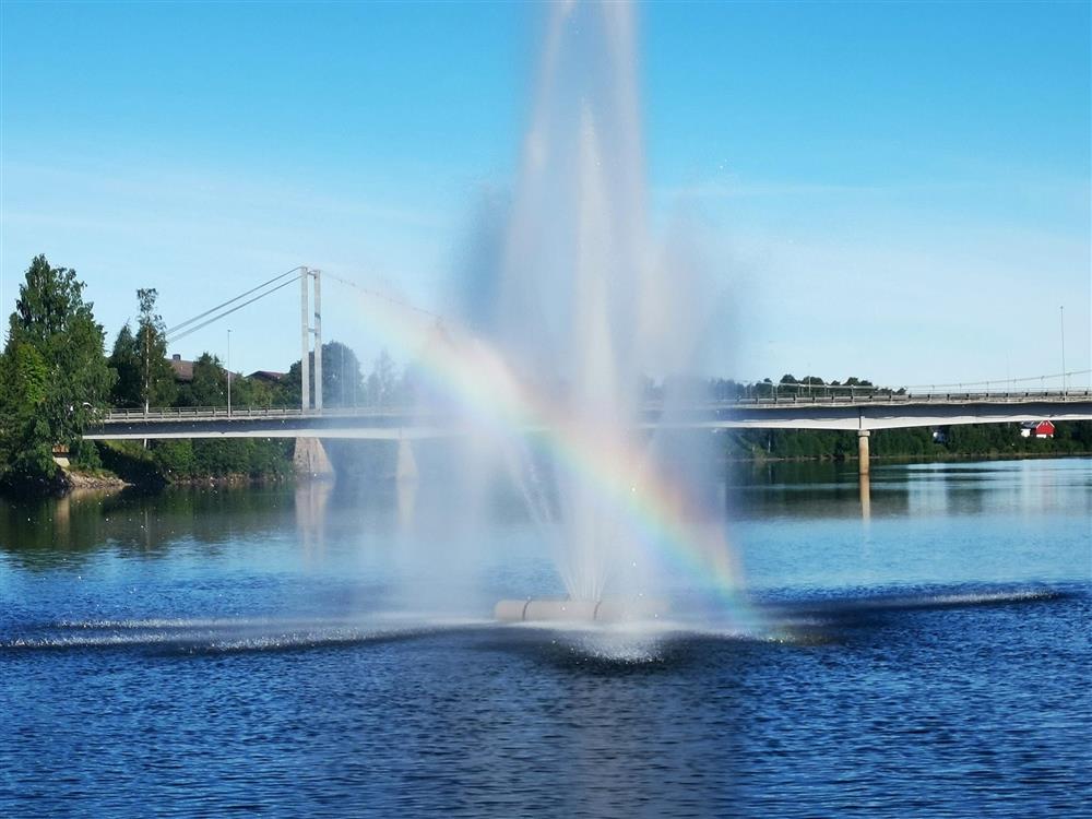 En fonte i en elv som gir en regnbue. - Klikk for stort bilde