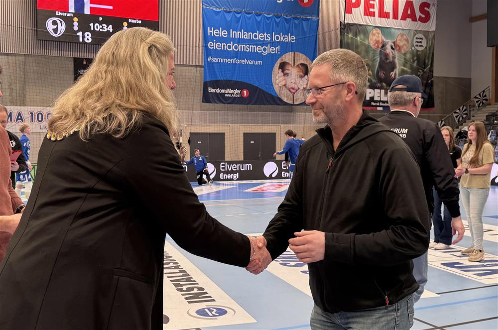 To personer som håndhilser i en idrettshall. - Klikk for stort bilde