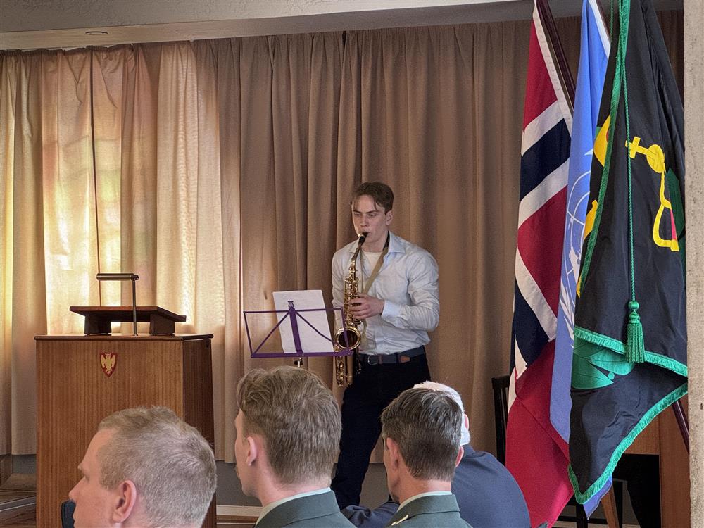 En gutt står på en scene og spiller saxofon. - Klikk for stort bilde
